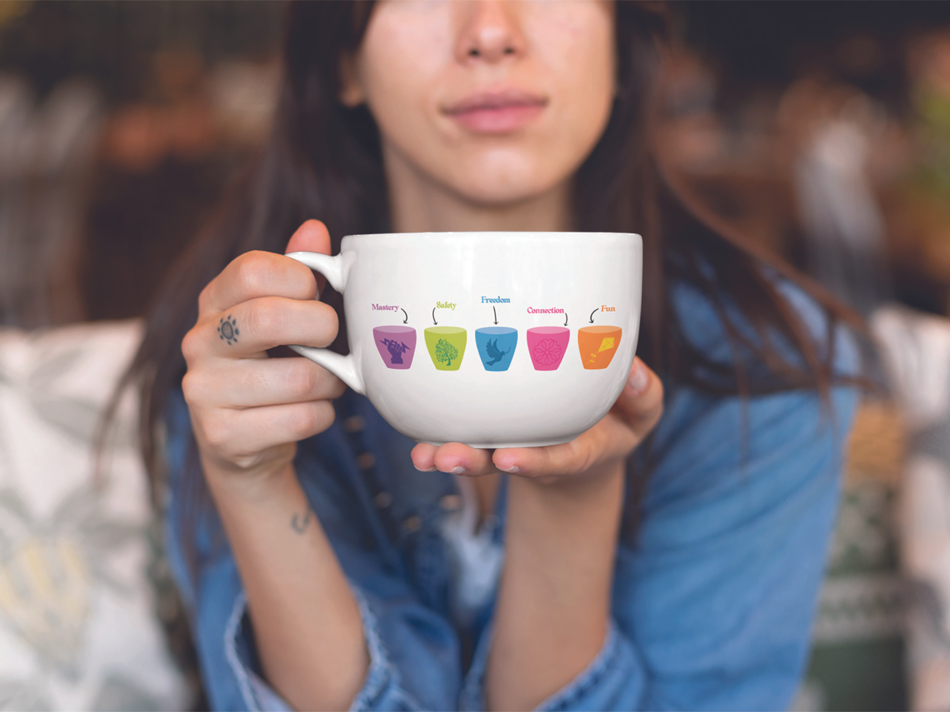 A woman holding a mug printed with the five Phoenix Cups